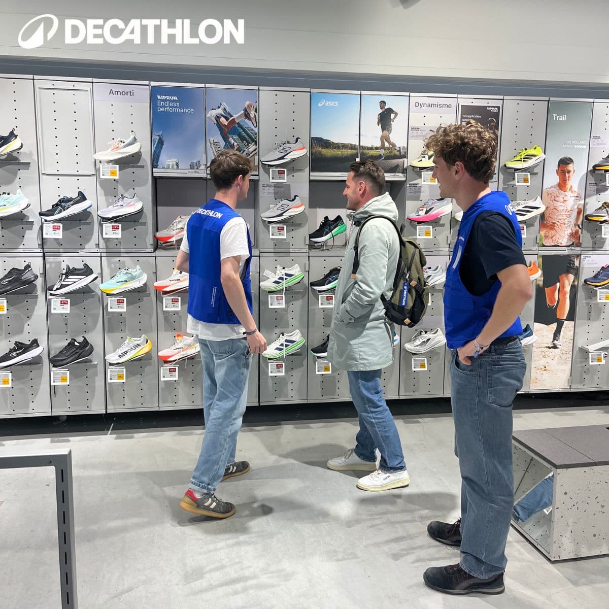 Journée en magasin Decathlon : vendeurs en gilet bleu échangeant dans le rayon running.